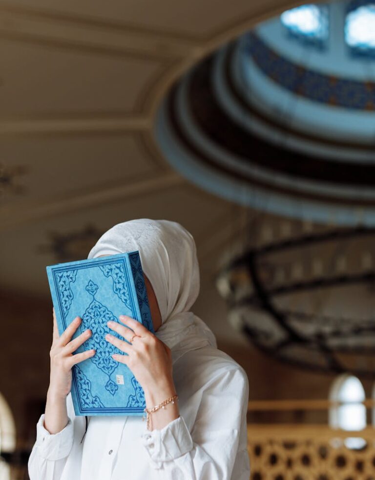 A woman in a hijab holding a blue book in a mosque, depicting devotion.